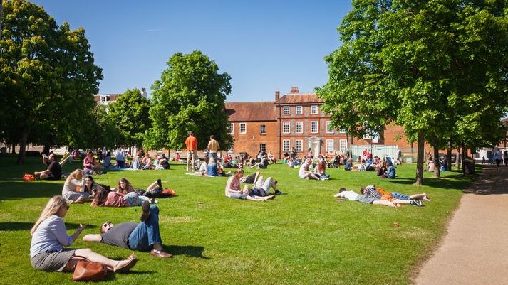 Pessoas relaxando nos terrenos da catedral em Winchester, Inglaterra