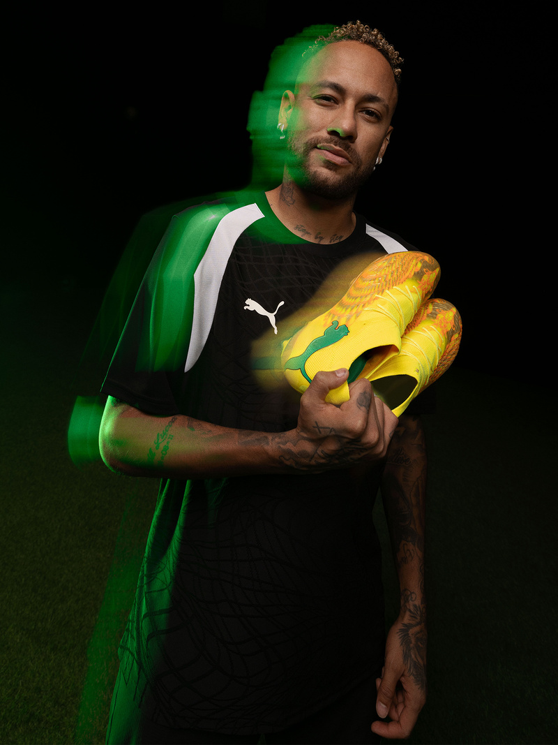 Neymar em fundo preto segurando com uma mão par de chuteiras