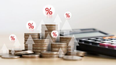 Imagem de moedas e uma calculadora com setas representando alta