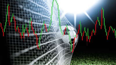Imagem mostra uma bola de futebol entrando na rede de um gol, com gráficos de ações e mercado financeiro na frente