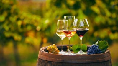 Três taças de vinho branco, rosa e tinto em um barril de madeira