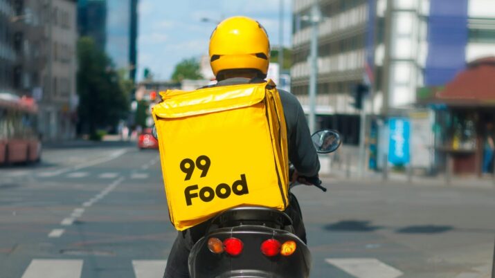 Motoboy com uma caixa amarela de entrega da 99Food