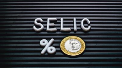 Imagem da palavra SELIC seguida do símbolo de porcentagem e uma moeda de R$ 1