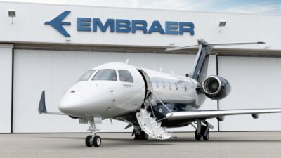 Um jato executivo da Embraer, o PRAETOR 500, em frente a marca da companhia.