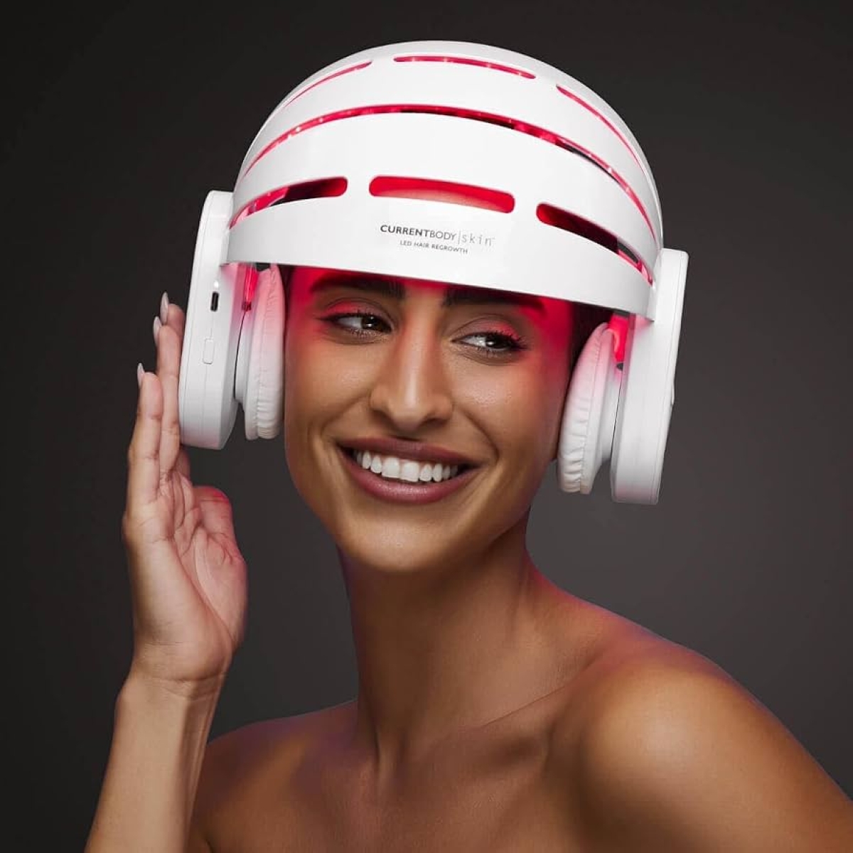 Mulher sorrindo e usando capacete de LED em fundo cinza
