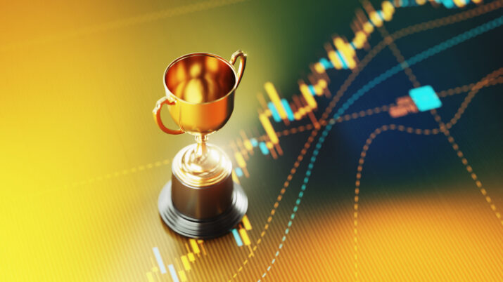Investment And Finance Concept - Gold Trophy Sitting On Yellow Financial Graph Background