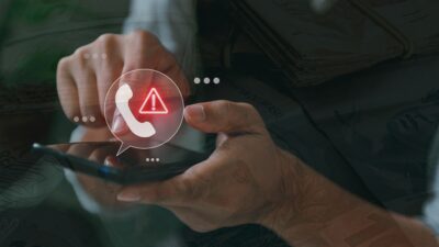 Celular com símbolo de alerta para representar golpes e fraudes digitais