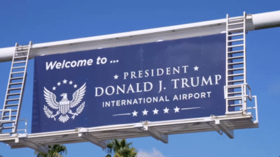 Placa de trânsito azul onde se lê em inglês: bem-vindos ao President Donald J. Trump International Airport
