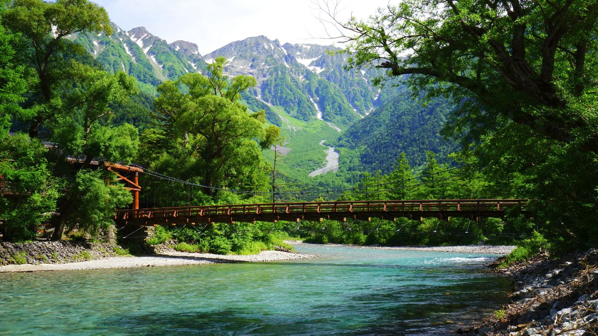 ponte sobre rio com montanha ao fundo