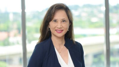Jeane Tsutsui, CEO do Fleury (FLRY3) em um fundo de árvores e sorrindo