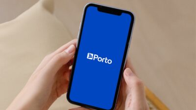 Pessoa segurando celular com logo da Porto (PSSA3).