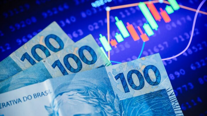 Gráfico de ações e notas de cem reais para representar a bolsa brasileira