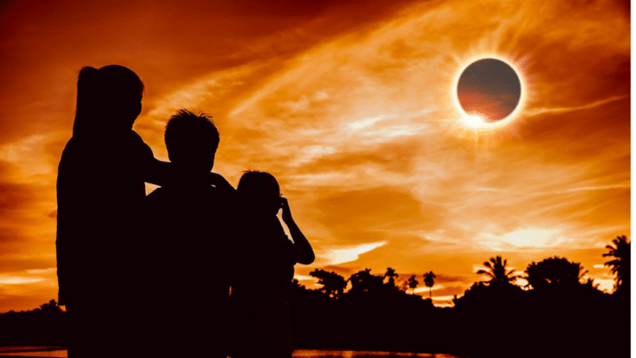 Três pessoas olhando para o eclipse solar total.