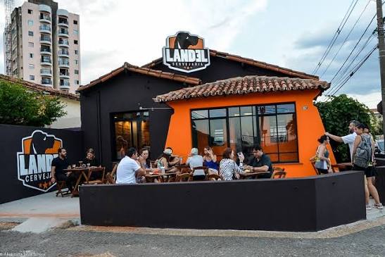 Pessoas sentadas em frente a uma tap house laranja