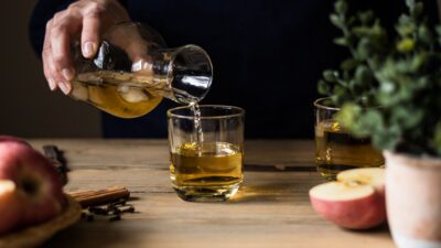 Bebida de fruta sendo servida em copo; à direita, uma maçã cortada ao meio