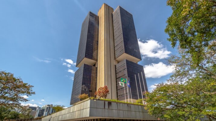 Imagem mostra o prédio do banco central visto de baixo. o céu está bem azul com poucas nuvens ao fundo