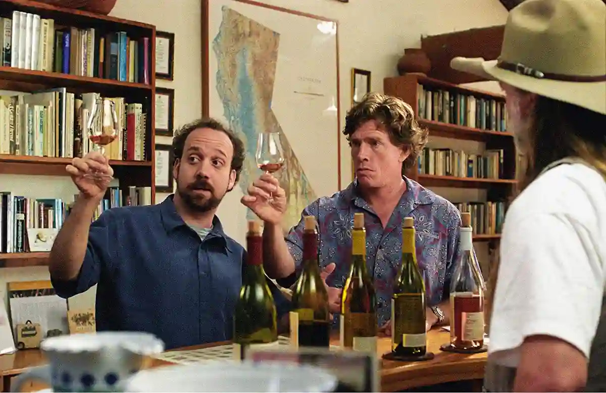 Paul Giamatti e Thomas Haden Church em cena de Sideways - Entre Umas e Outras, os dois seguram taças de vinho