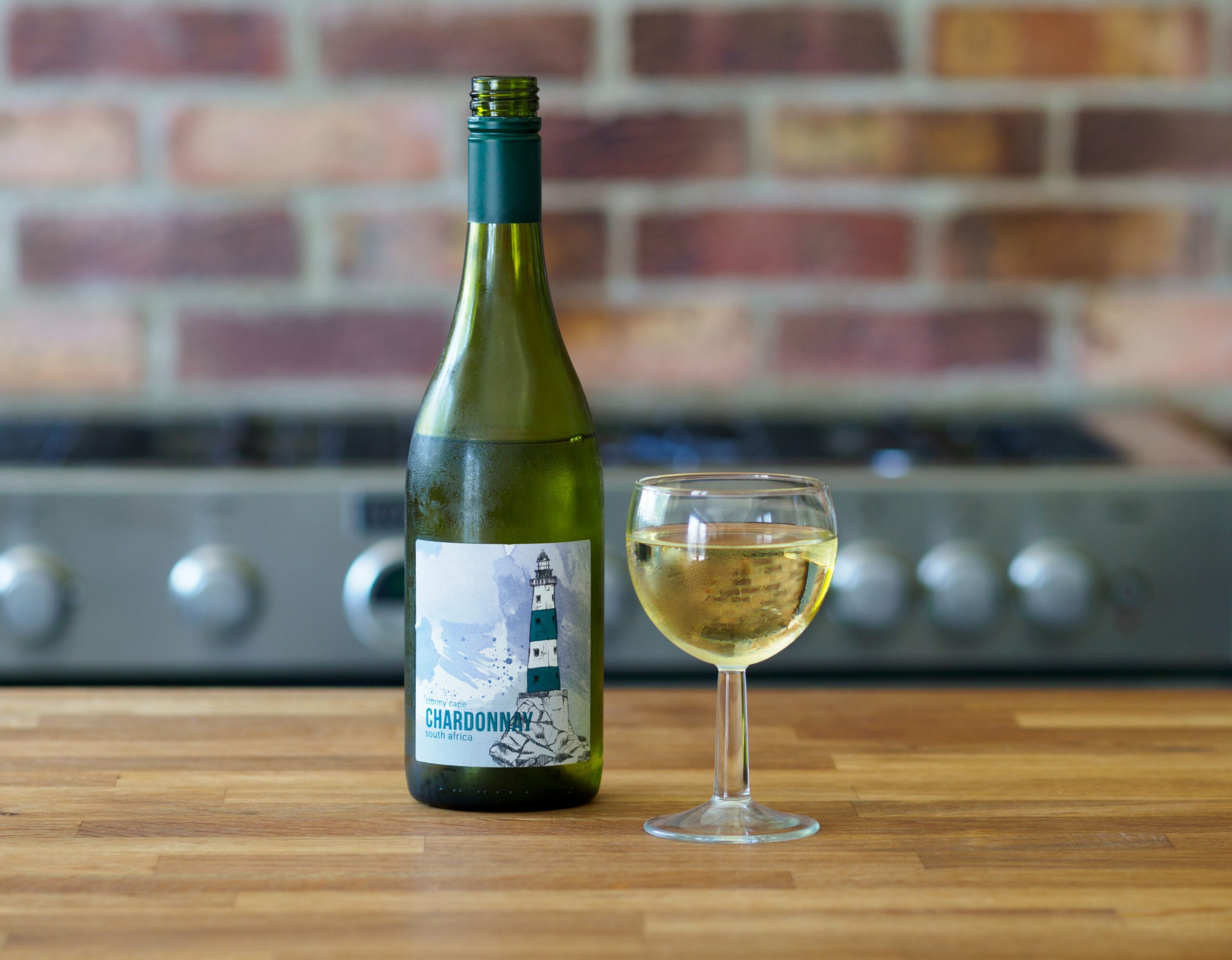 Garrafa de vinho branco sobre uma mesa com uma taça servida pela metade