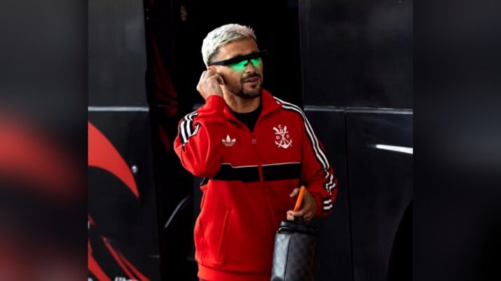 Jogador do Flamengo usando óculos com luz verde na chegada ao Maracanã. O acessório utiliza fototerapia para estimular a retina e auxiliar na manutenção do estado de alerta durante a noite.
