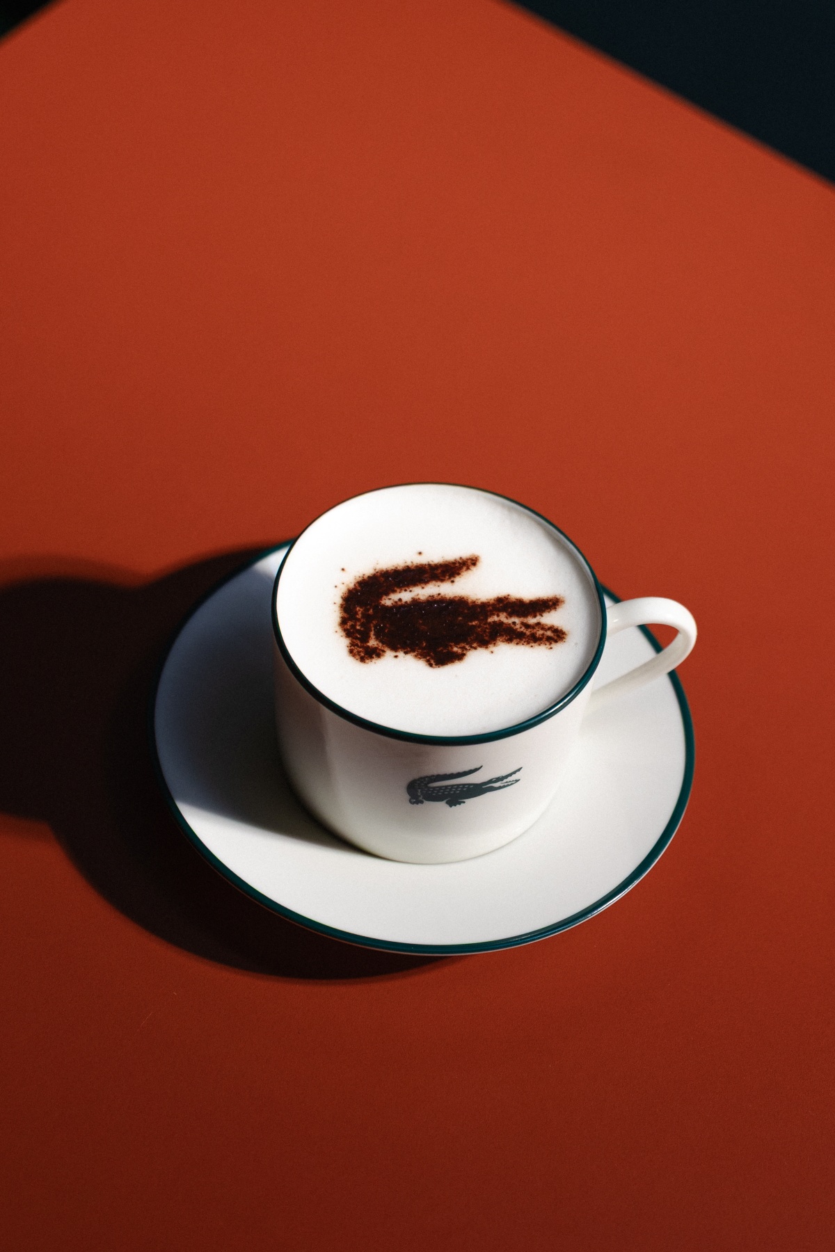 Capuccino com espuma branca e com logo de crocodilo em cacau - em fundo terra-cota