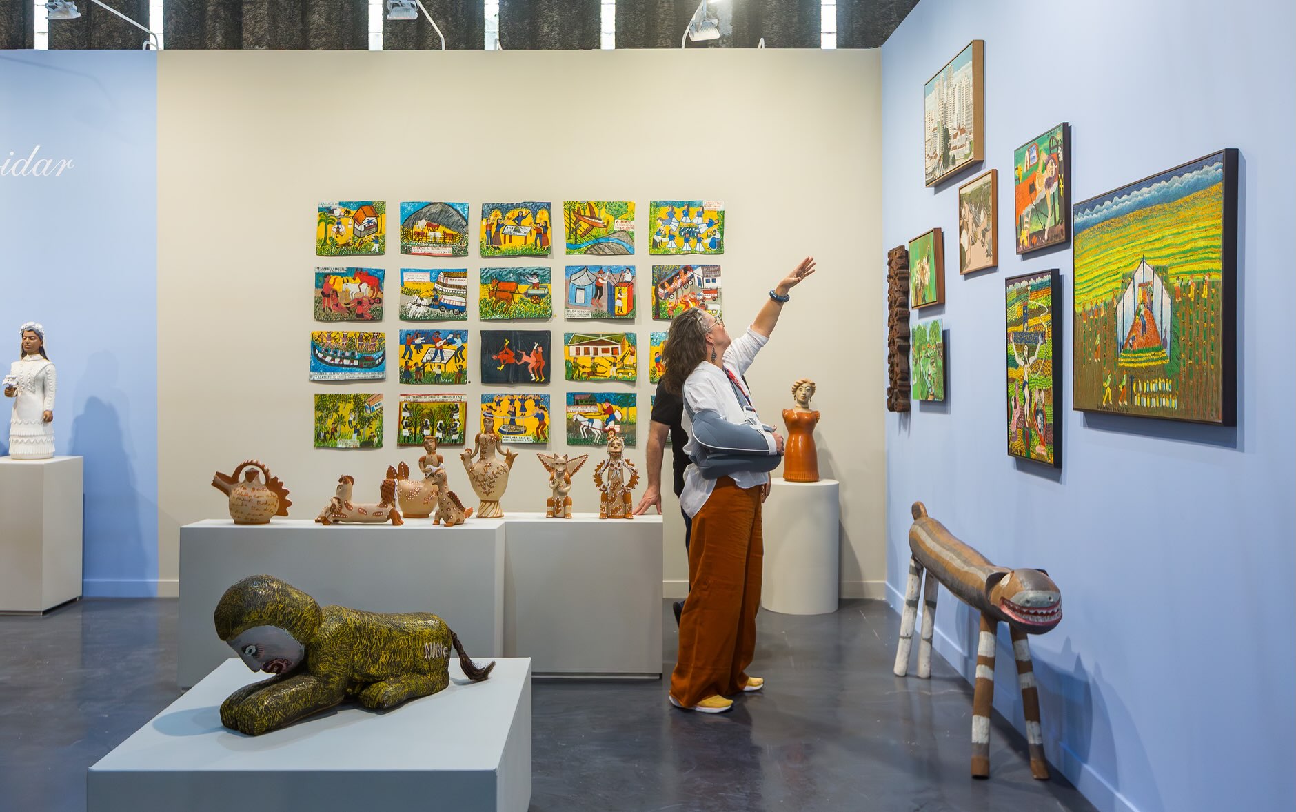 Duas pessoas vistas de lado em meio a obras de arte
