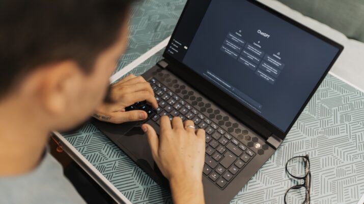 Um homem trabalhando em um laptop com software de IA aberto na tela, usando óculos.