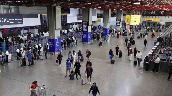 Saguão do Aeroporto Internacional de Guarulhos com passageiros em área de check-in; novas regras da Anac afetam passageiros indisciplinados em voos domésticos.