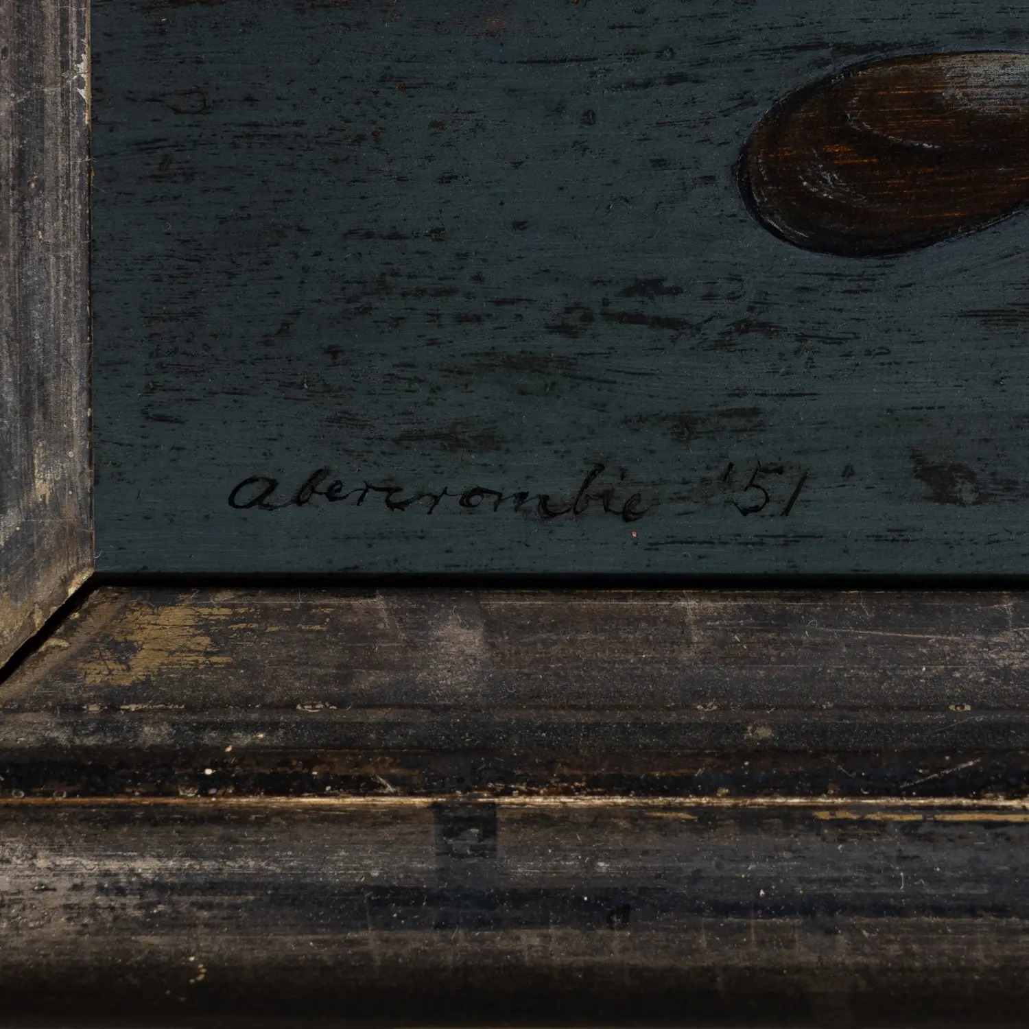 Close em uma pintura escura com moldura de madeira e assinatura manuscrita na parte inferior.
