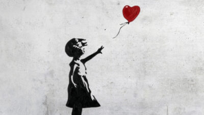 Grafite em preto e branco de uma menina estendendo o braço para um balão vermelho em forma de coração.