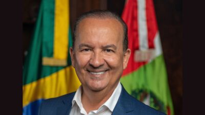 Jorginho Melo de terno entre bandeira do Brasil e