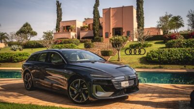 Perua Audi preta estacionada diante de uma casa com jardim e piscina.