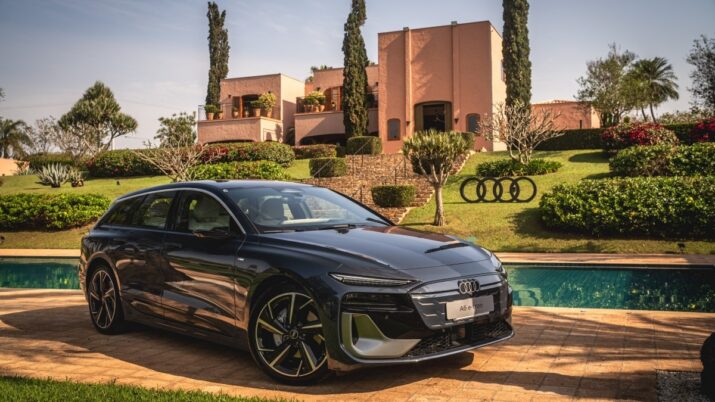 Perua Audi preta estacionada diante de uma casa com jardim e piscina.