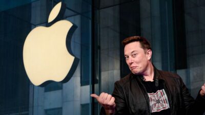 Montagem que traz o prédio da Apple ao lado esquerdo, com o símbolo da maçã ao lado, e Elon Musk no lado direito, olhando para a maçã