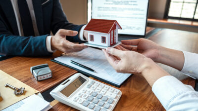 O corretor de imóveis apresentando o empréstimo imobiliário e entregando as chaves ao cliente após a assinatura do contrato para comprar a casa com o formulário de solicitação de propriedade aprovado