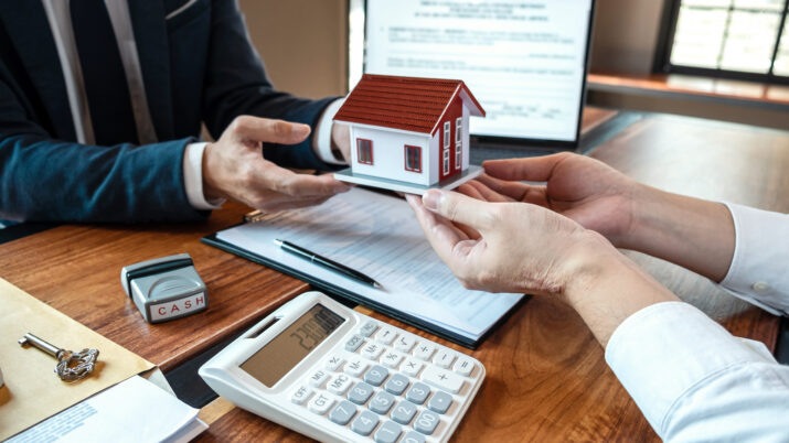 O corretor de imóveis apresentando o empréstimo imobiliário e entregando as chaves ao cliente após a assinatura do contrato para comprar a casa com o formulário de solicitação de propriedade aprovado