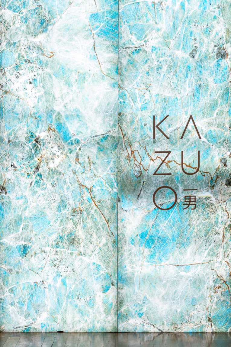 Parede de mármore azul e branco com o nome Kazuo em letras marrons.