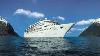 Navio de cruzeiro branco navegando em mar aberto entre duas montanhas cobertas de neve.