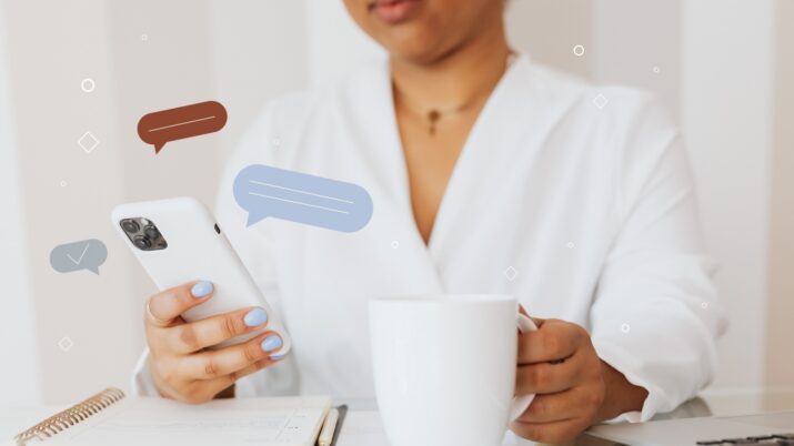 Pessoa segurando um celular e uma caneca sobre a mesa, com ícones de mensagens sobrepostos à imagem.