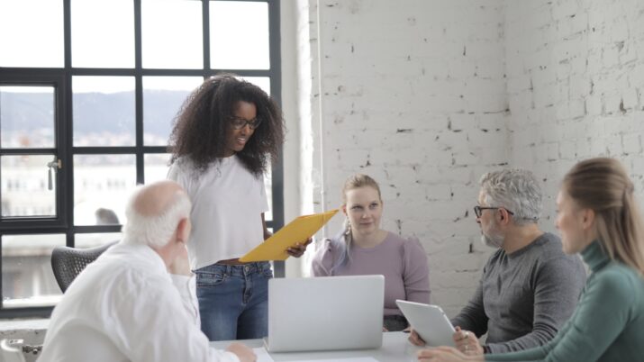 Uma equipe diversificada de adultos colabora em um ambiente de escritório moderno com laptops e documentos.