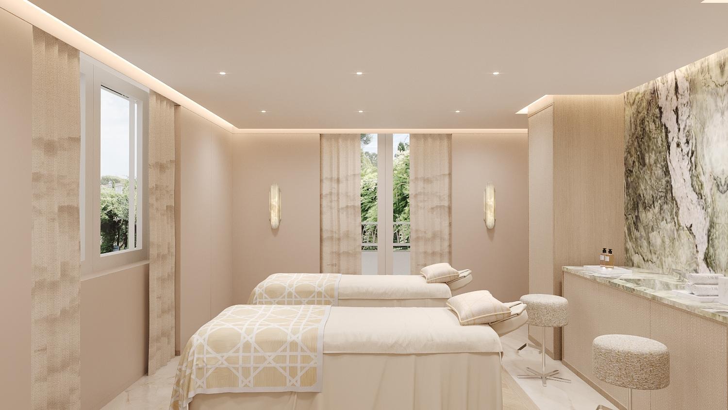 Sala de spa com duas macas, paredes em tons claros, janelas com cortinas e bancada lateral em mármore.