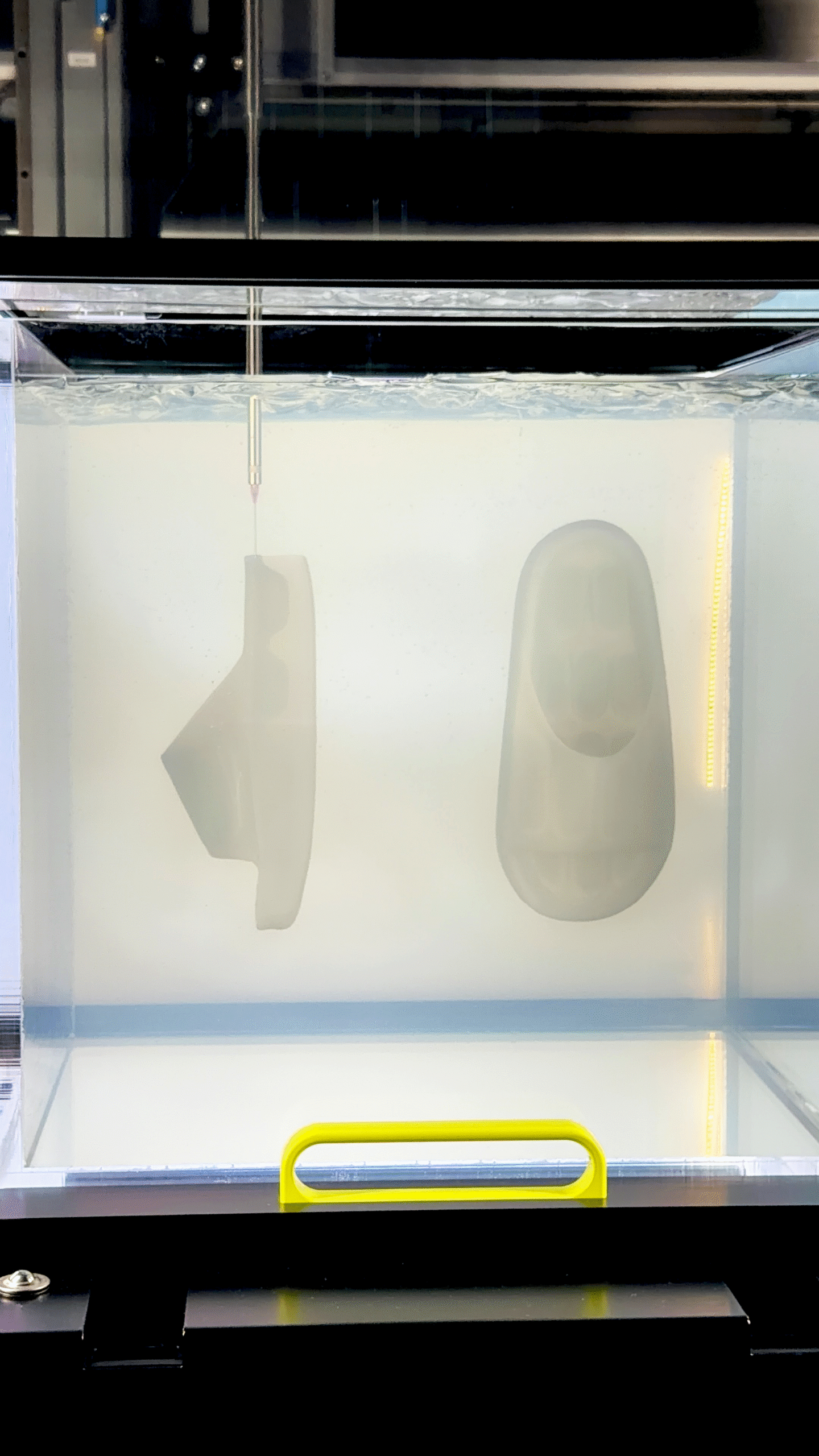 Chinelo branco suspenso dentro de um tanque transparente com água e iluminação lateral amarela.